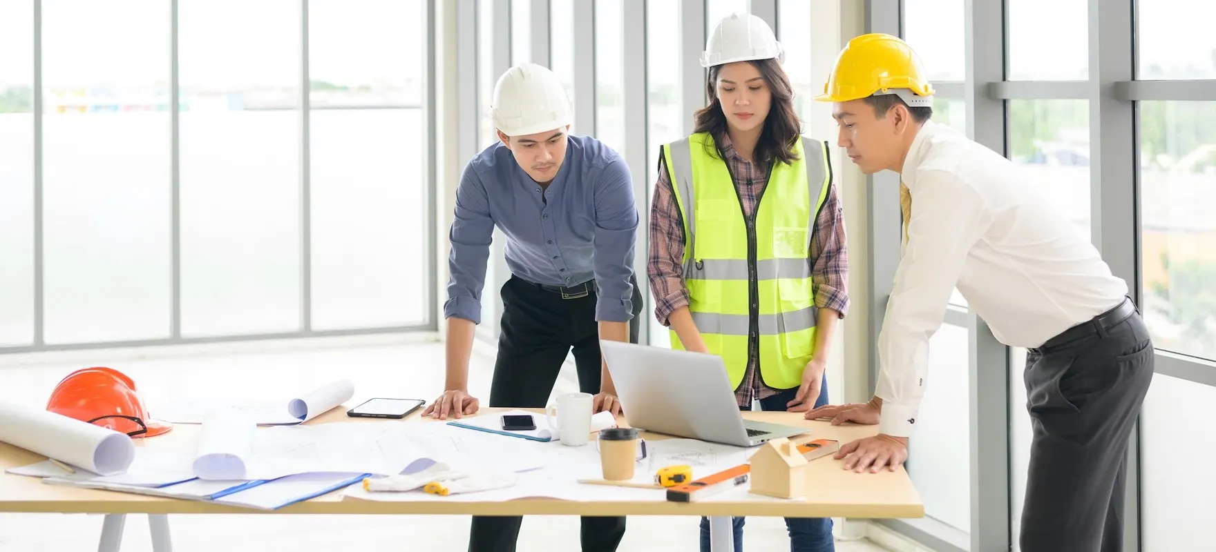 A construction team reviewing blueprints and project plans on a laptop