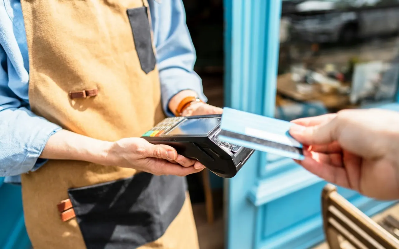 A cafe owner processing a card payment at the counter
